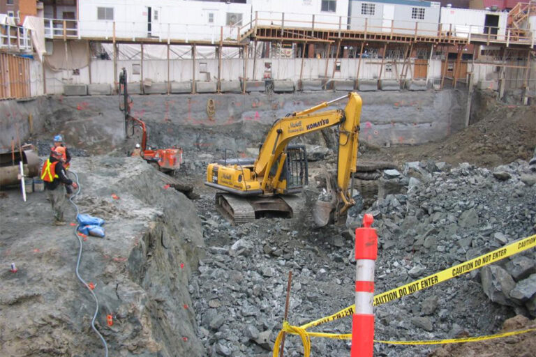 A machine works at a construction site as two people look on.