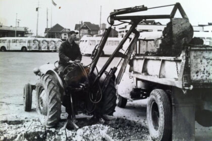 A black-and-white photo captures a man operating machinery.